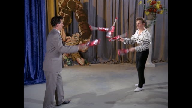 Slow motion, Winston and Paul Foxwell juggle 6 clubs between them.
