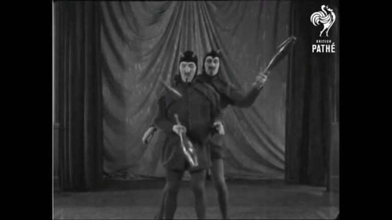 Two men dressed as devils perform a club runaround on a Pathe video